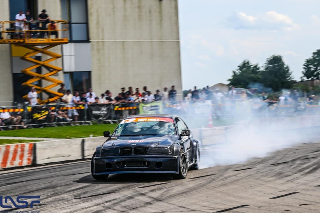 Juodas BMW drifto automobilis trasoje su žiūrovais